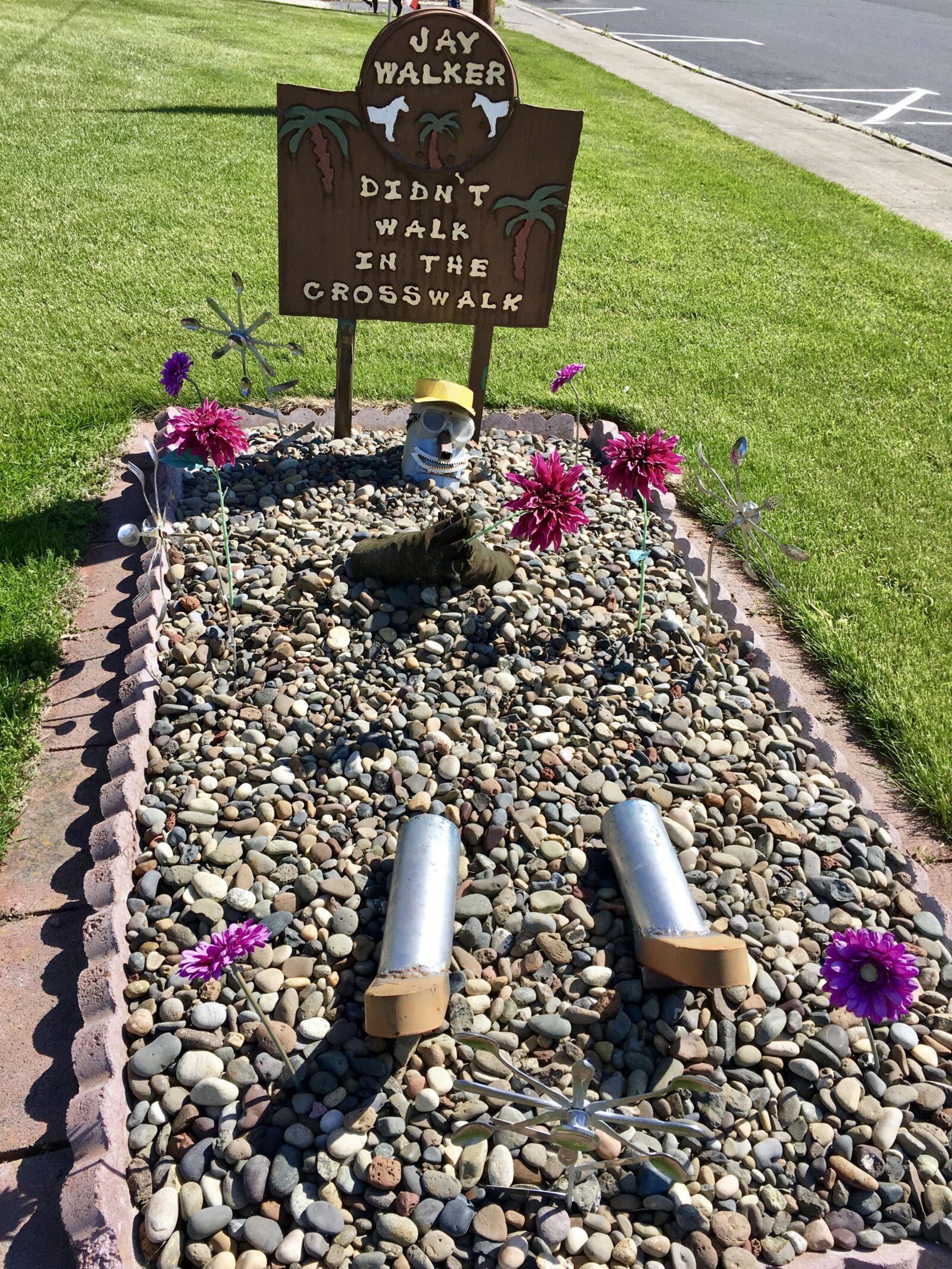 An area done in the style of a cemetery plot has a sign "Jay Walker, Didn't walk in the crosswalk."  In the rocky area are what remains of "Jay," a metallic pair of legs and smiling head.